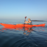 A person on a red canoe in the sea.