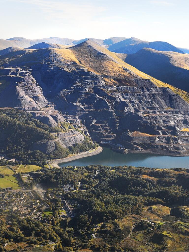 An aerial shot of a slate quarry with blue reservoirs below.