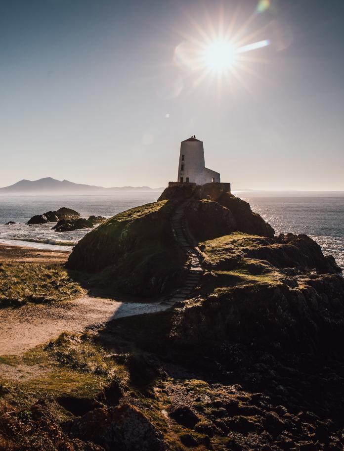 Goleudy Llanddwyn a'r traeth yn haul cryf y gaeaf