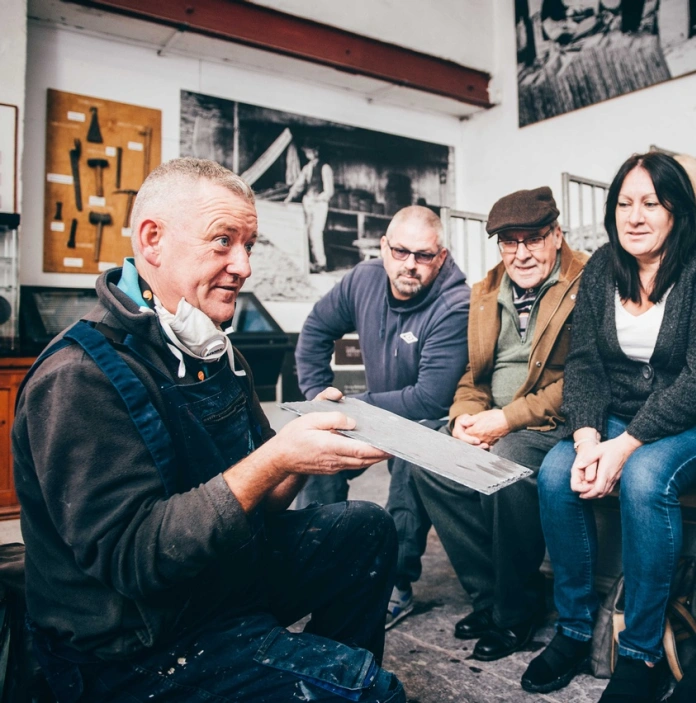 A group of people watching a demonstration on slate splitting.