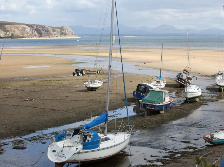 Cychod a chychod hwylio wedi'u hangori ar y traeth gyda'r llanw allan ar draeth Abersoch.