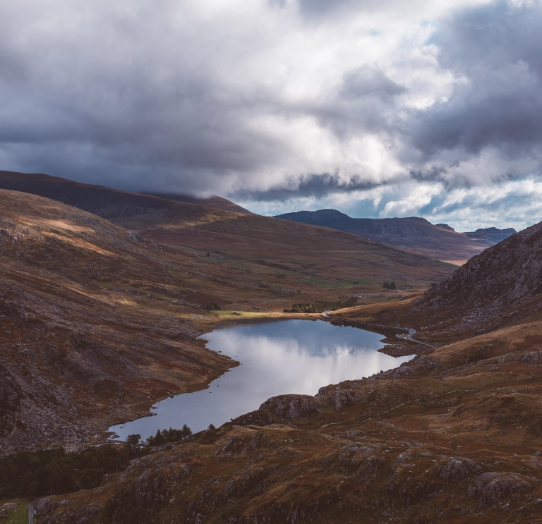 Golygfa o'r llyn wedi'i amgylchynu gan fynyddoedd ar y ddwy ochr ac yn y cefndir