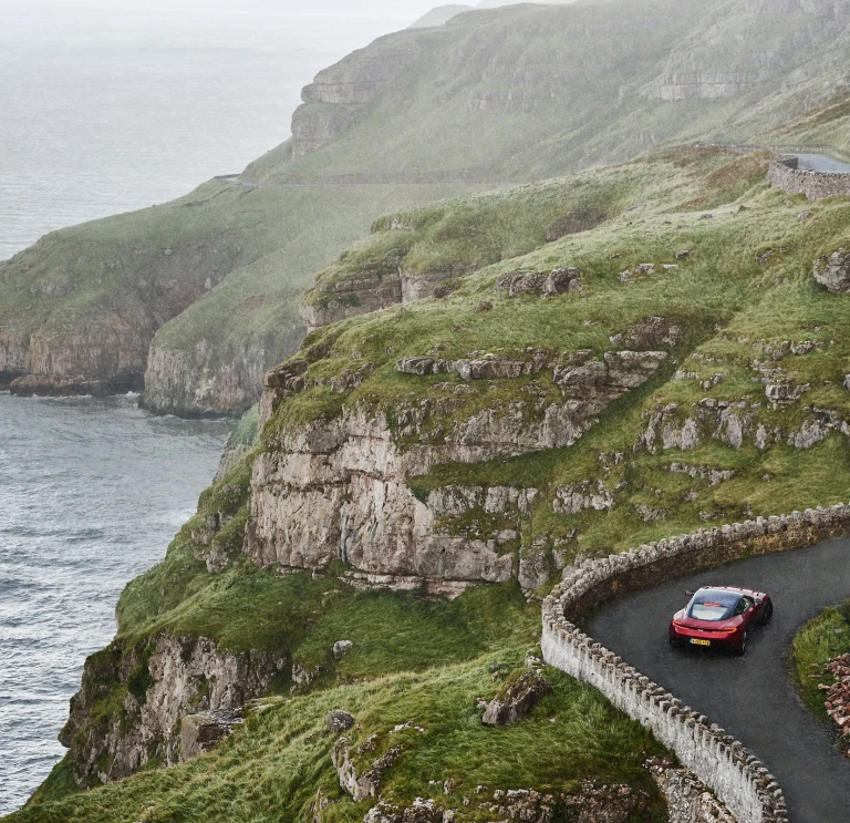 Car yn gyrru ar hyd ffordd droellog gyda'r môr ar yr ochr chwith