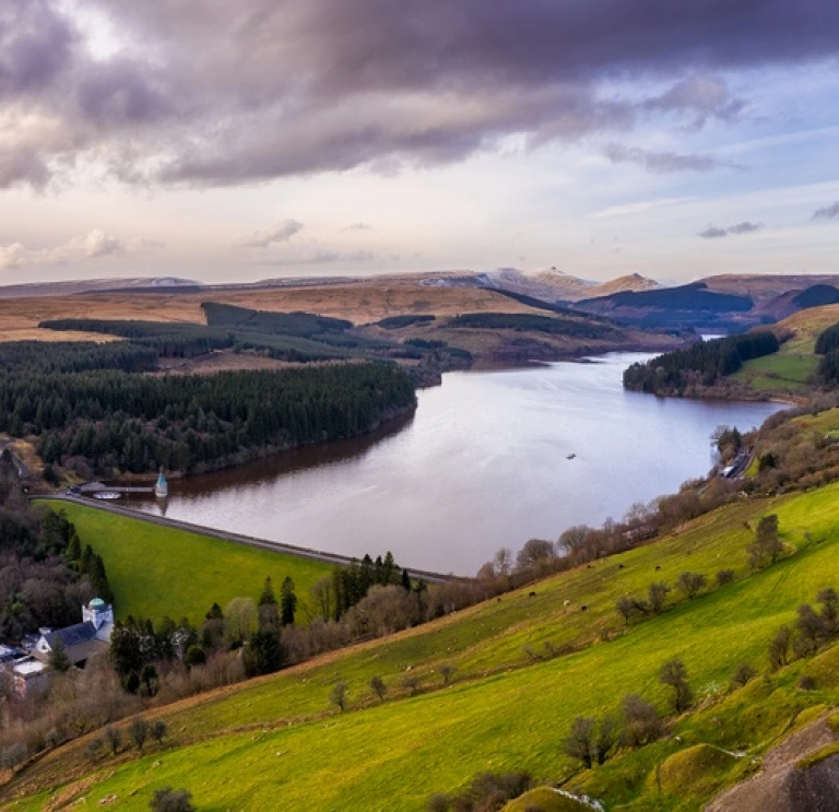 Golygfa o gronfa ddŵr wedi'i amgylchynu gan fynyddoedd