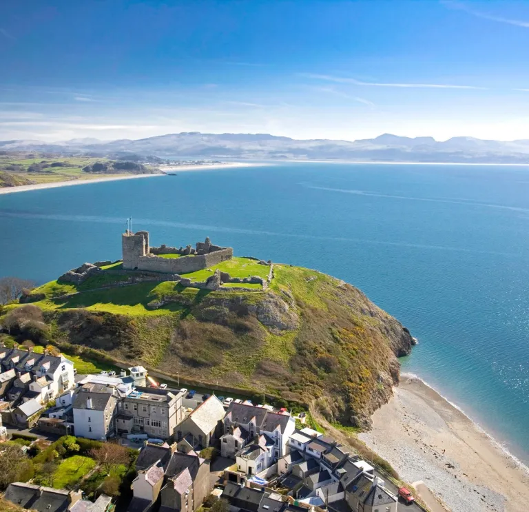 Golygfa o'r awyr o Gastell Cricieth ar y bryn, y dref yn y tu blaen a'r môr a bryniau pell yn y cefndir